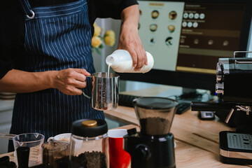 Barista pouring milk into cappuccino, creating latte art in cozy café setting, showcasing morning preparation, craftsmanship, and coffee culture indoors.