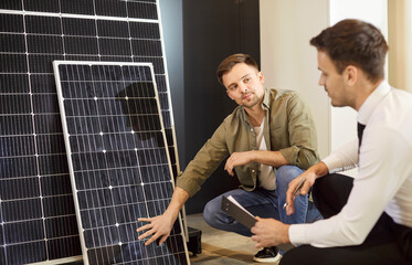 Shop assistant helping a customer choose a solar panel. Salesman at the store talks about...