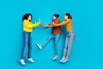 Obraz premium Three diverse young friends in casual outfits posing with playful and animated gestures against a vibrant blue background