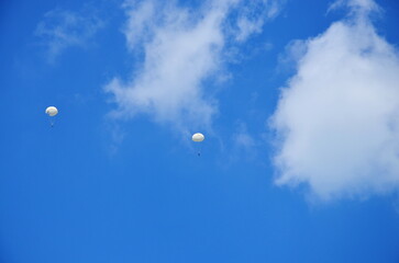 view of  blue sky with clouds and parashutists descending to the airfield