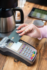 A woman's hand pays with a credit card at a payment terminal in a cafe