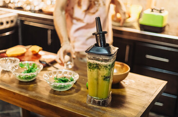 Making fresh mango-lime juice with mint in a blender. Vegan smoothie prep in a bright tropical kitchen. Healthy, plant-based, and eco-friendly cooking lifestyle