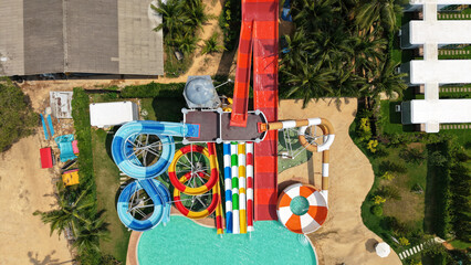 Aerial view captures the vibrant and exciting atmosphere of a water park, with colorful waterslides twisting and turning around pools and amidst lush tropical greenery