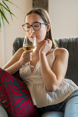 A young woman drinking wine in available light