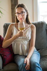 A young woman drinking wine in available light