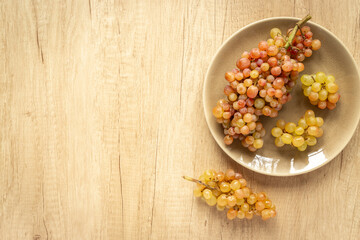 Plate full of ripe yellow grapes, top view