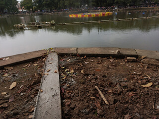 Murky Lake by Concrete Bank Undergoing Construction on Sunny Day