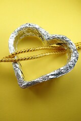 Srebrne serce na żółtym tle, przeplecione żółtymi sznurkami © tomo81