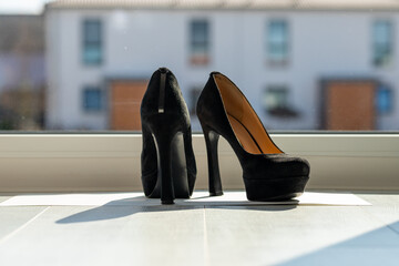 Black ladies pumps on the floor in front of a window