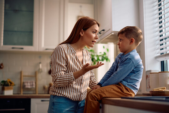 Mother scolding her son in kitchen.