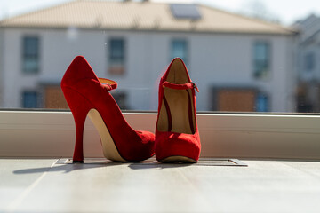 Red ladies pumps on the floor in front of a window