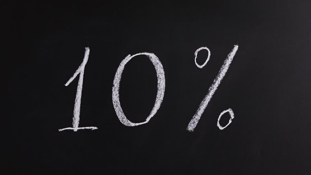 Closeup view of hand writing 10% on black chalkboard background. Concept of promotion sale announcement, advertising, discount, tax cut, tariffs increase, off season price decrease, special rate offer