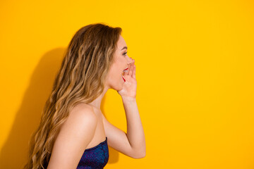 Cheerful young woman shouting joyfully against bright yellow background conveying excitement and...