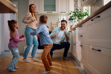 Cheerful parents having fun and dancing with their children at home.