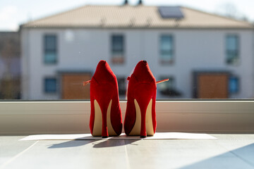 Red ladies pumps on the floor in front of a window