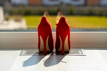 Red ladies pumps on the floor in front of a window