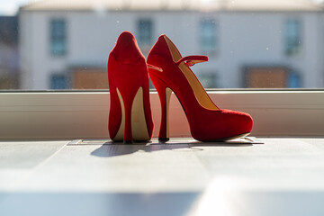 Red ladies pumps on the floor in front of a window