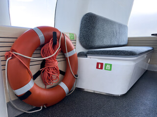 Safety equipment inside electric passenger boat including lifebuoy and seating with fire extinguisher and life jacket icons. Clean modern interior for public water transport.