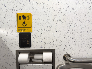 Close up of emergency assistance button and call system in accessible toilet. Yellow tactile sign...