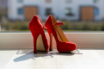 Red ladies pumps on the floor in front of a window