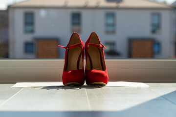 Red ladies pumps on the floor in front of a window
