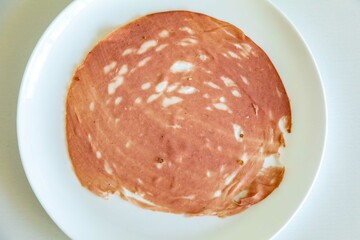 Close-up of a sliced bologna on a white plate