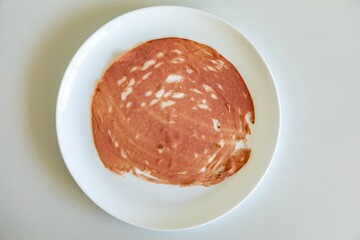 Close-up of a sliced bologna on a white plate