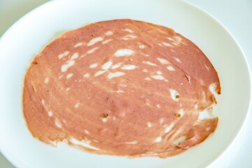 Close-up of a sliced bologna on a white plate