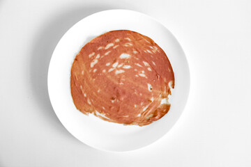 Close-up of a sliced bologna on a white plate