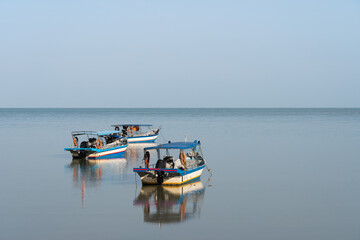 Three fishing boats resting on the calm sea in Batu Ferringhi, Malaysia