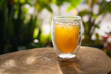 Refreshing Iced Tea Drink in Double-Walled Glass on Wooden Table Outdoors