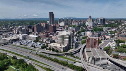 Cars and trucks driving through Albany, NY downtown beside Hudson river and past rural...