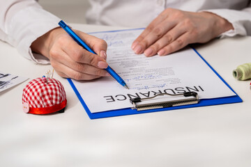 Person Signing an Insurance Document with a Blue Pen
