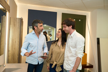 Couple designing home interior with advisor in furniture showroom