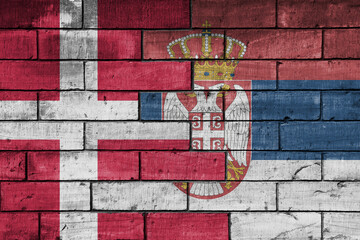 colourful painted big national flag of serbia and flag of denmark on a massive old brick wall background. concept