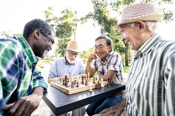 Group of senior friends playing chess at the park