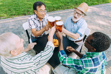 Group of senior friends drinking a beer at the park