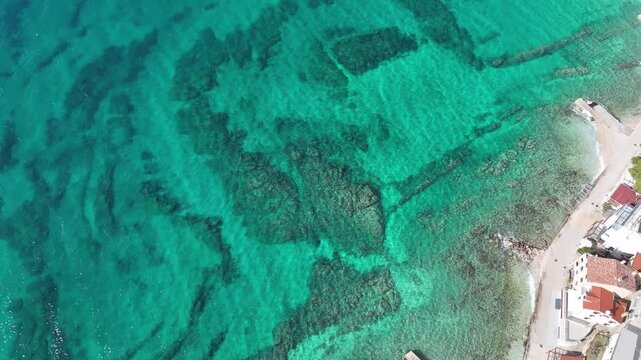 Baska beach and coastline with crystal-clear turquoise water, marina boats, city street, sunny summer mood captured from drone view on Krk Island. Baska vacations town in Adriatic sea