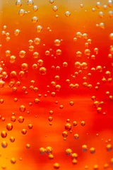 Bright orange liquid filled with fizzy bubbles captures the light © faveteart