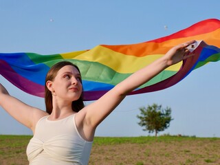 Rainbow flag of an LGBT organization waving against a blue sky. LGBT pride flags include lesbians,...