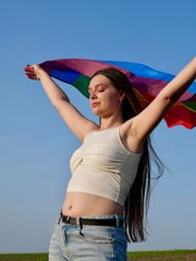 Rainbow flag of an LGBT organization waving against a blue sky. LGBT pride flags include lesbians,...