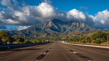 Fototapeta premium A long, empty highway with a mountain in the background