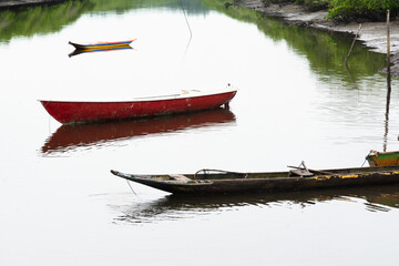 A mighty river with anchored fishing and transport boats and canoes.
