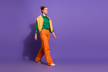 Adorable woman walking confidently with casual vibrant style against a purple background