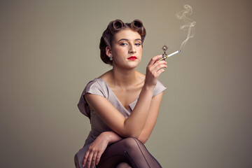 Obraz premium A woman in vintage attire smoking a cigarette with a decorative holder.
