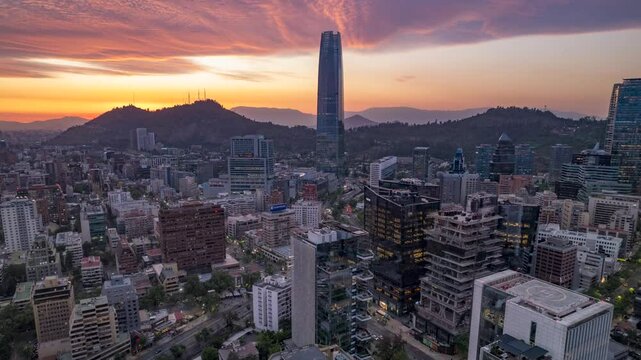 Santiago, Chile &ndash; October 19, 2024: Drone descends laterally over Las Condes during golden sunset, with the Costanera Center tower and surrounding cityscape bathed in warm light.