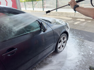 Closeup of male driver washing his car with contactless high pressure water jet