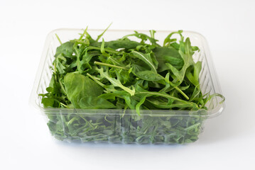 Arugula and spinach leaves in tray isolated on white. Fresh salad leaves in plastic container.