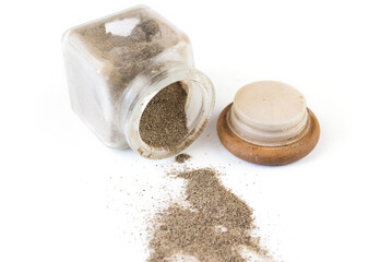 black ground pepper in a glass pepper shaker on a white background.
