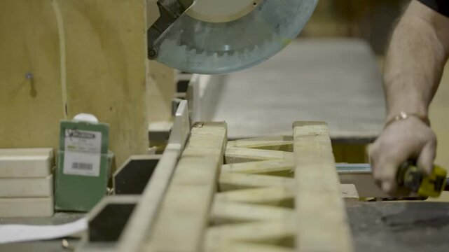Detailed slow motion shot of a carpenter slicing wood with an automatic circular saw during commercial manufacturing